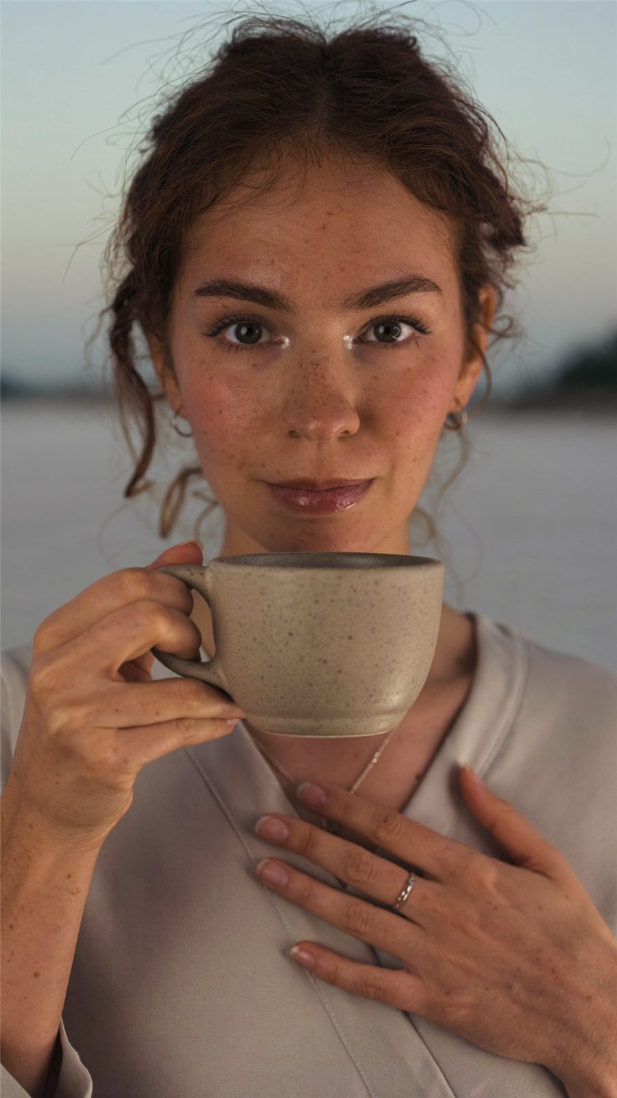 Ayleen, matrona, sosteniendo una taza de cerámica en luz de atardecer